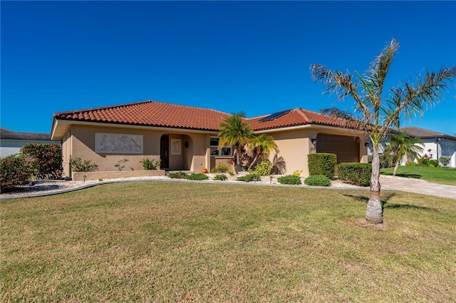 mediterranean / spanish home with solar panels, a garage, and a front lawn