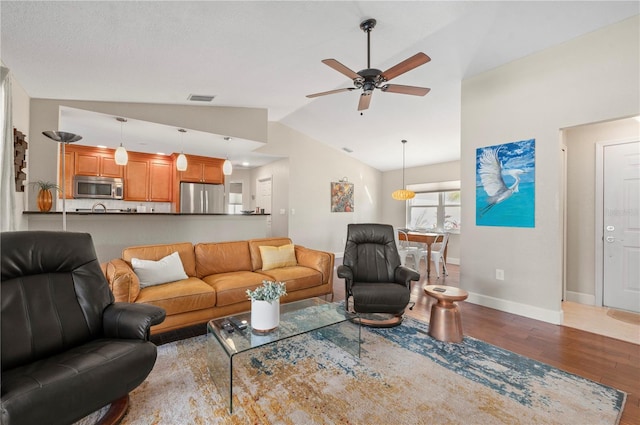 living room featuring hardwood / wood-style floors, vaulted ceiling, and ceiling fan