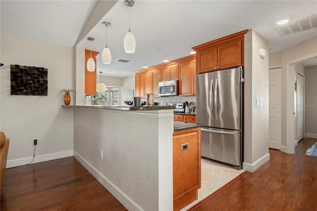 kitchen featuring decorative light fixtures, kitchen peninsula, appliances with stainless steel finishes, and light hardwood / wood-style flooring