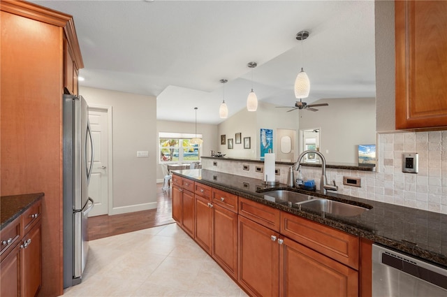 kitchen featuring appliances with stainless steel finishes, lofted ceiling, dark stone countertops, and sink