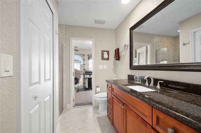 bathroom featuring tile patterned flooring, vanity, toilet, and an enclosed shower