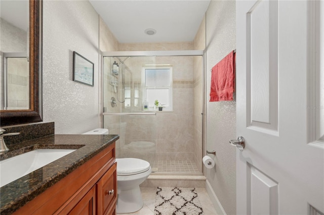 bathroom featuring tile patterned flooring, vanity, a shower with shower door, and toilet