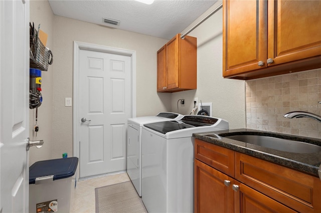 laundry room with cabinets, sink, washer and dryer, light tile patterned floors, and a textured ceiling