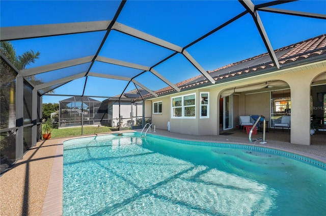 view of swimming pool with glass enclosure, ceiling fan, and a patio