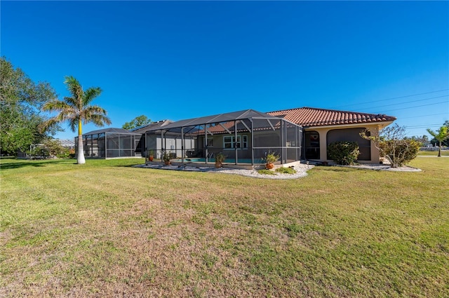 rear view of house with a swimming pool, glass enclosure, and a lawn