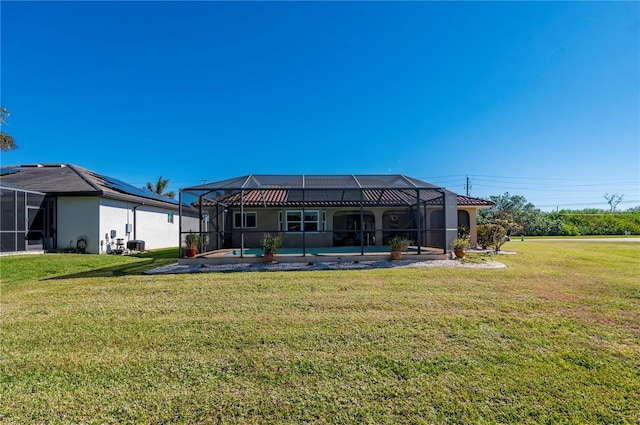 back of house featuring a lawn, glass enclosure, and a pool