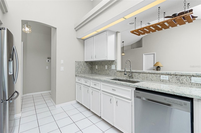 kitchen with sink, hanging light fixtures, light tile patterned floors, white cabinets, and appliances with stainless steel finishes