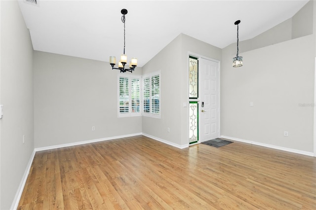 spare room with an inviting chandelier, wood-type flooring, and vaulted ceiling