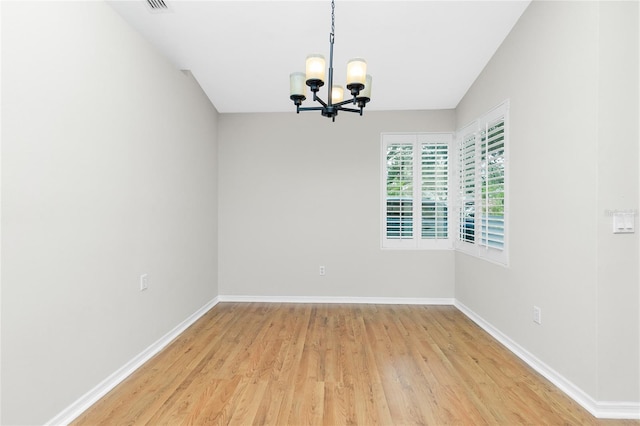 empty room featuring a chandelier, light hardwood / wood-style floors, and lofted ceiling