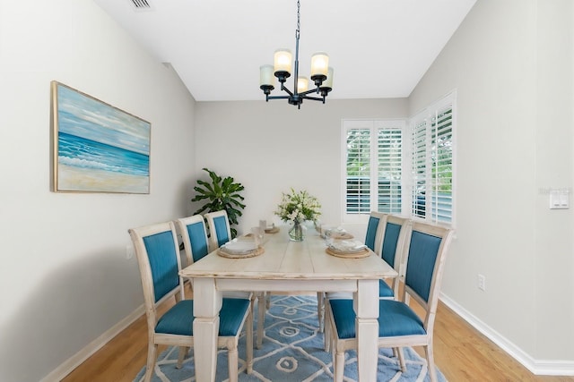 dining space with an inviting chandelier, lofted ceiling, and hardwood / wood-style flooring