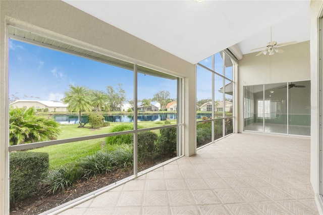 unfurnished sunroom featuring ceiling fan and a water view