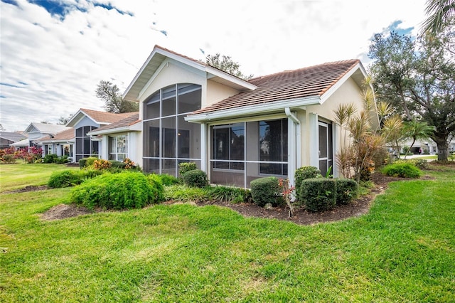 back of property featuring a sunroom and a lawn