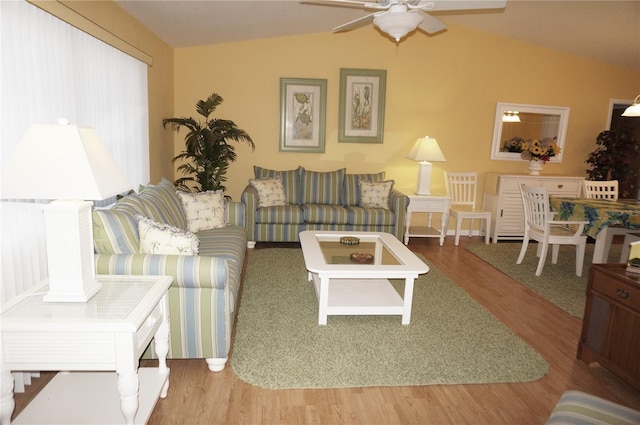 living room with ceiling fan, wood-type flooring, and vaulted ceiling