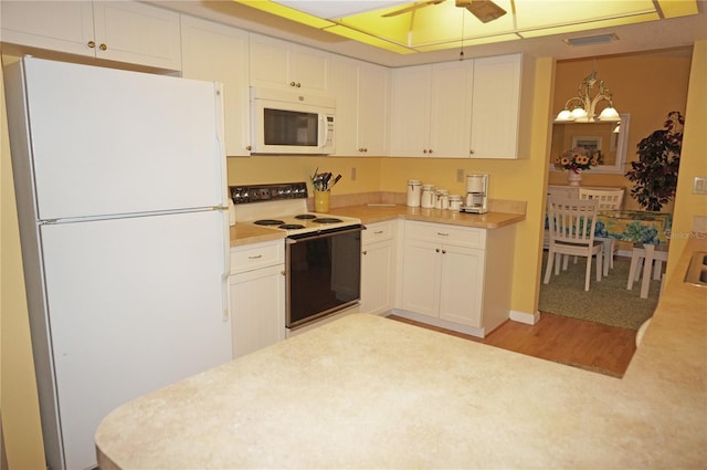 kitchen with ceiling fan with notable chandelier, white appliances, white cabinetry, and hanging light fixtures