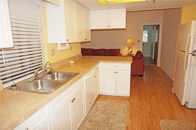 kitchen with sink, kitchen peninsula, white appliances, white cabinets, and light wood-type flooring