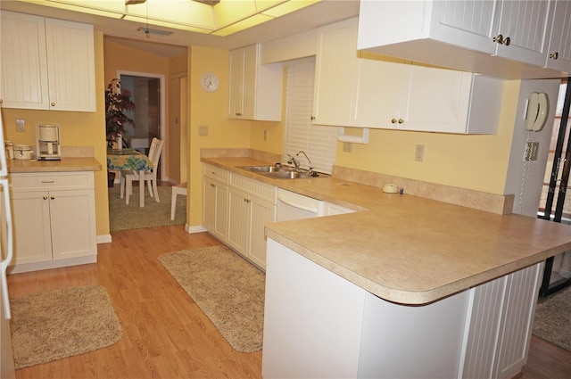 kitchen with kitchen peninsula, white cabinets, light hardwood / wood-style flooring, and sink