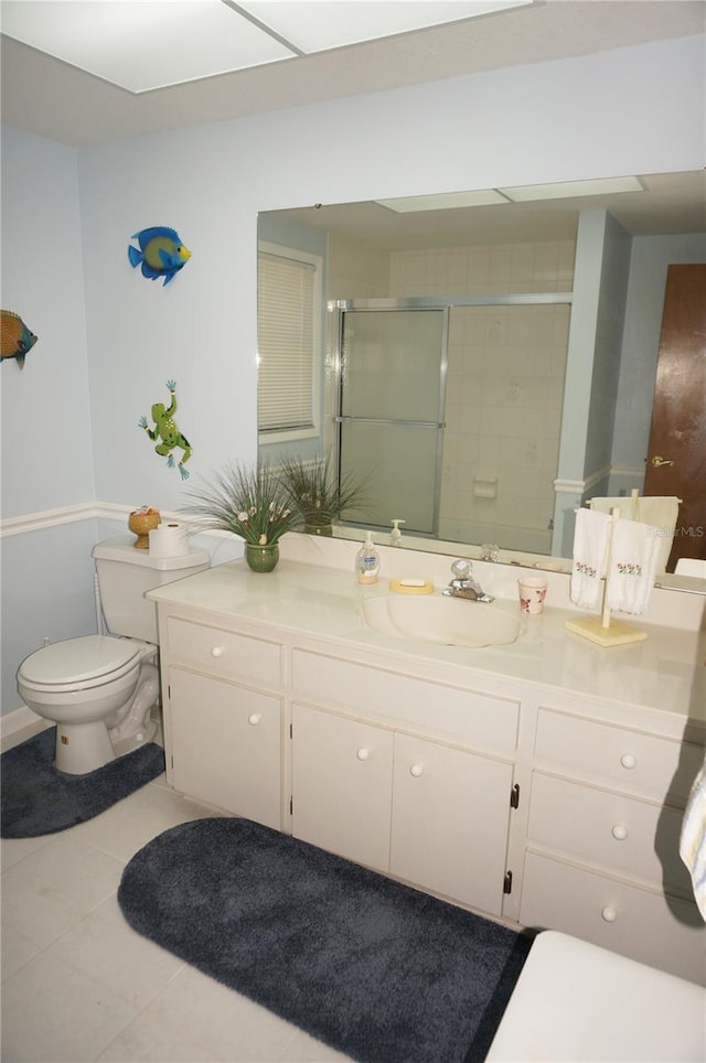 bathroom featuring tile patterned flooring, vanity, toilet, and walk in shower