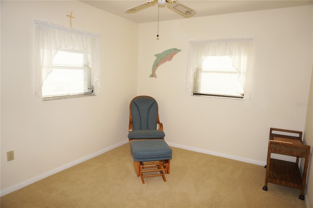 living area featuring light carpet and ceiling fan