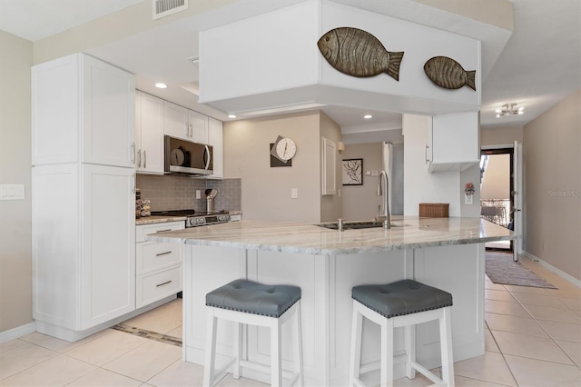 kitchen featuring white cabinetry, sink, light stone counters, light tile patterned flooring, and appliances with stainless steel finishes