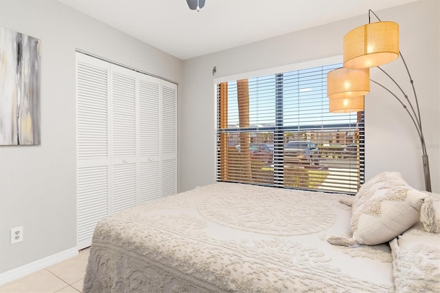 tiled bedroom with ceiling fan, multiple windows, and a closet