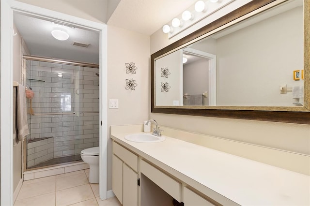 bathroom featuring tile patterned flooring, vanity, a shower with door, and toilet