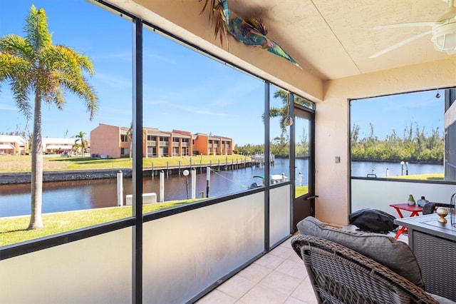 sunroom with ceiling fan and a water view