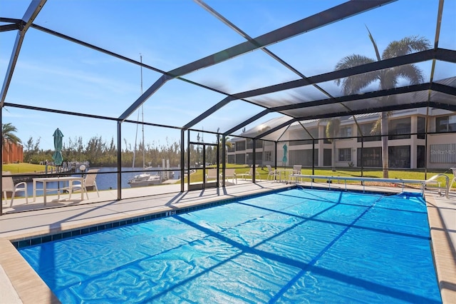 view of pool with glass enclosure, a water view, and a patio