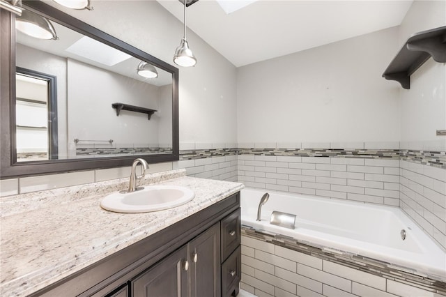 bathroom with vanity, tiled tub, and a skylight