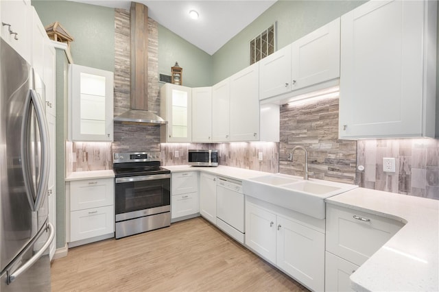 kitchen featuring backsplash, vaulted ceiling, appliances with stainless steel finishes, light hardwood / wood-style floors, and white cabinetry