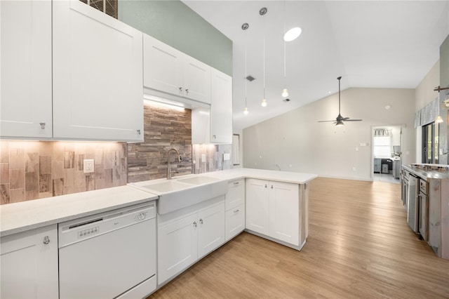 kitchen featuring white dishwasher, kitchen peninsula, white cabinetry, and sink