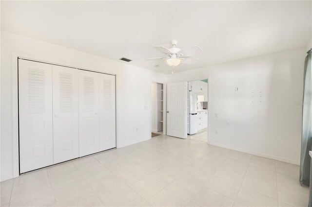 unfurnished bedroom featuring ceiling fan, white refrigerator, and a closet