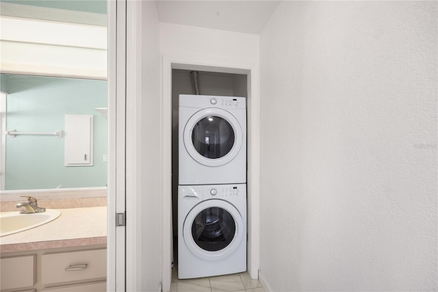 clothes washing area with stacked washer / dryer, sink, and light tile patterned floors