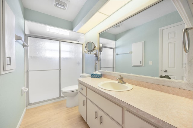 bathroom with vanity, toilet, wood-type flooring, and a shower with door