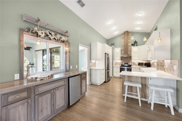 kitchen featuring kitchen peninsula, decorative light fixtures, stainless steel appliances, and white cabinetry