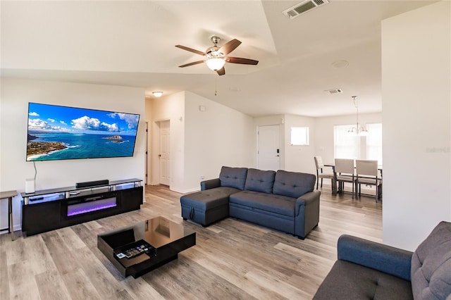 living room with ceiling fan with notable chandelier and light wood-type flooring