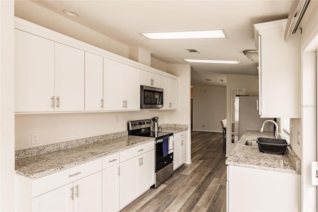 kitchen with sink, light stone counters, appliances with stainless steel finishes, white cabinets, and hardwood / wood-style flooring