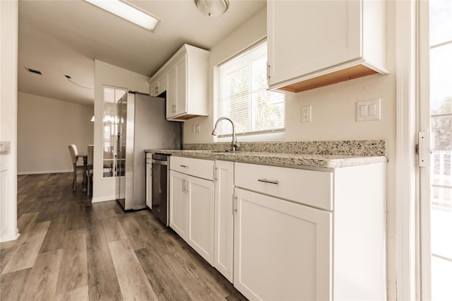 kitchen with light stone counters, sink, hardwood / wood-style flooring, dishwasher, and white cabinets