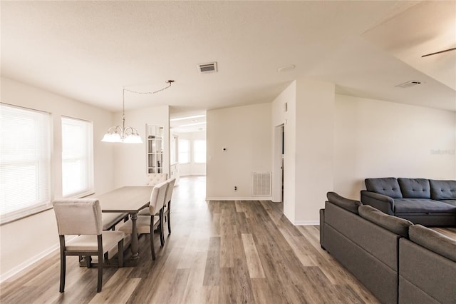 dining area featuring a wealth of natural light, wood-type flooring, and ceiling fan with notable chandelier