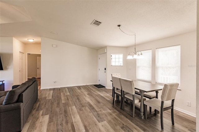 dining space with hardwood / wood-style floors and an inviting chandelier