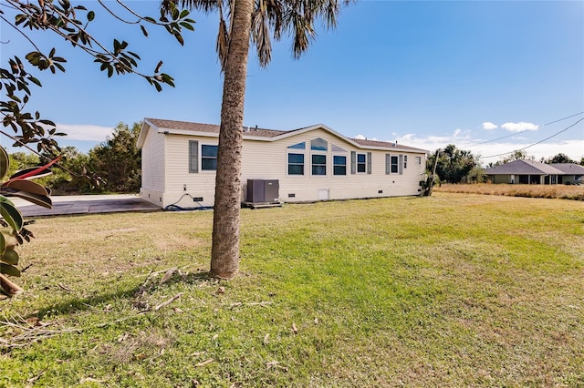 rear view of property with a lawn and cooling unit