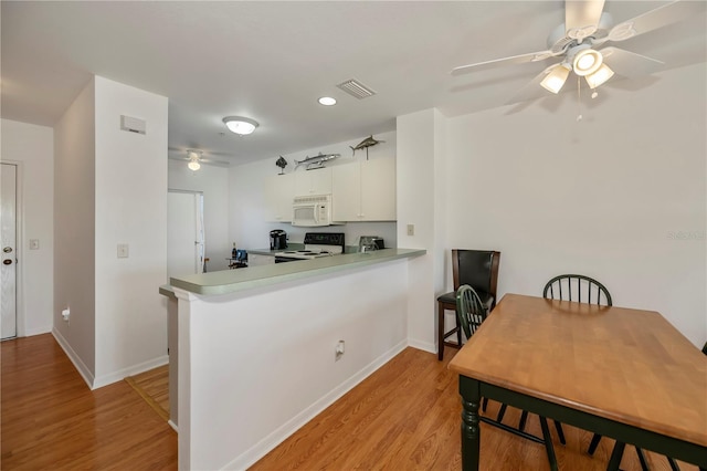 kitchen featuring kitchen peninsula, white cabinets, light hardwood / wood-style floors, and white appliances