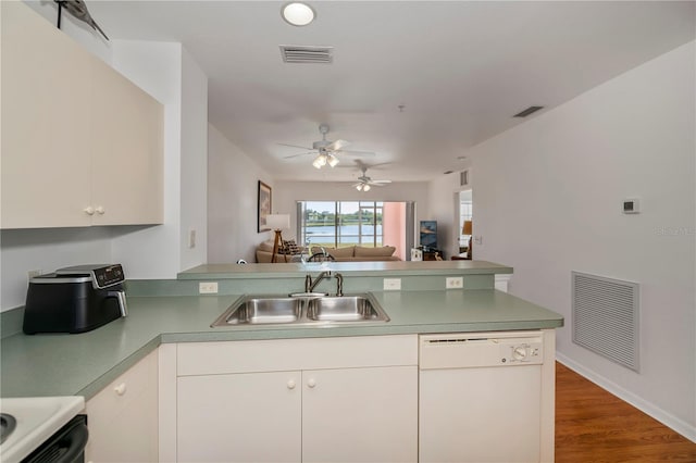 kitchen with kitchen peninsula, dark hardwood / wood-style flooring, white dishwasher, sink, and white cabinetry