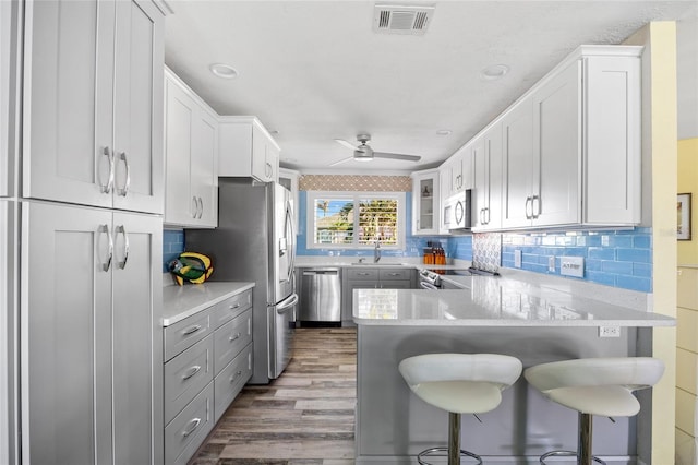 kitchen with kitchen peninsula, stainless steel appliances, sink, white cabinets, and a breakfast bar area