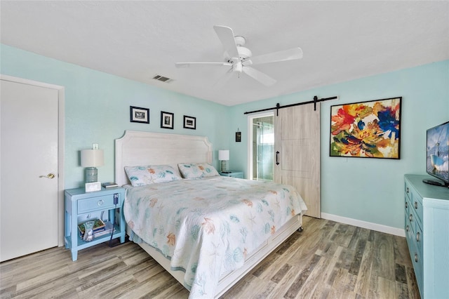 bedroom featuring a barn door, ceiling fan, and wood-type flooring