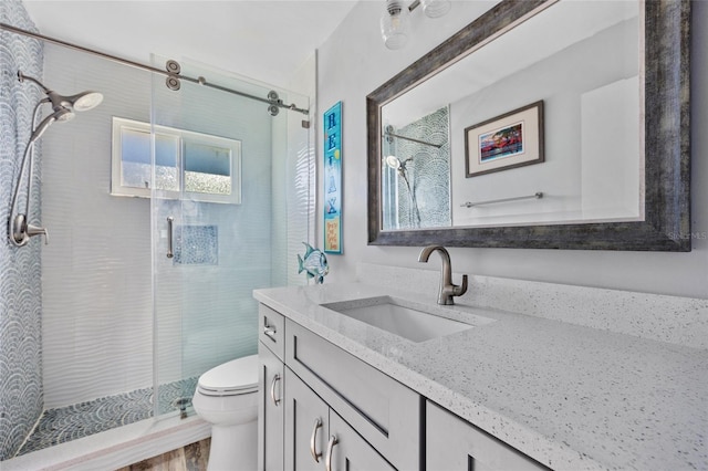 bathroom featuring tiled shower, hardwood / wood-style floors, vanity, and toilet