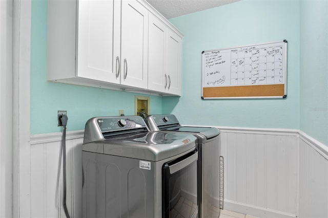 laundry room with cabinets, a textured ceiling, and separate washer and dryer