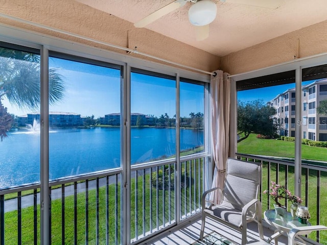 unfurnished sunroom with a wealth of natural light, a water view, and ceiling fan