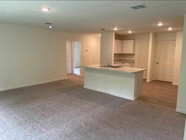 kitchen featuring white cabinetry, a center island with sink, carpet floors, and sink