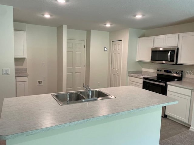 kitchen with a center island with sink, white cabinets, sink, and stainless steel appliances