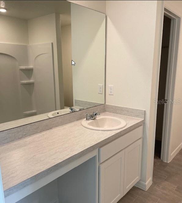 bathroom featuring wood-type flooring, vanity, and walk in shower